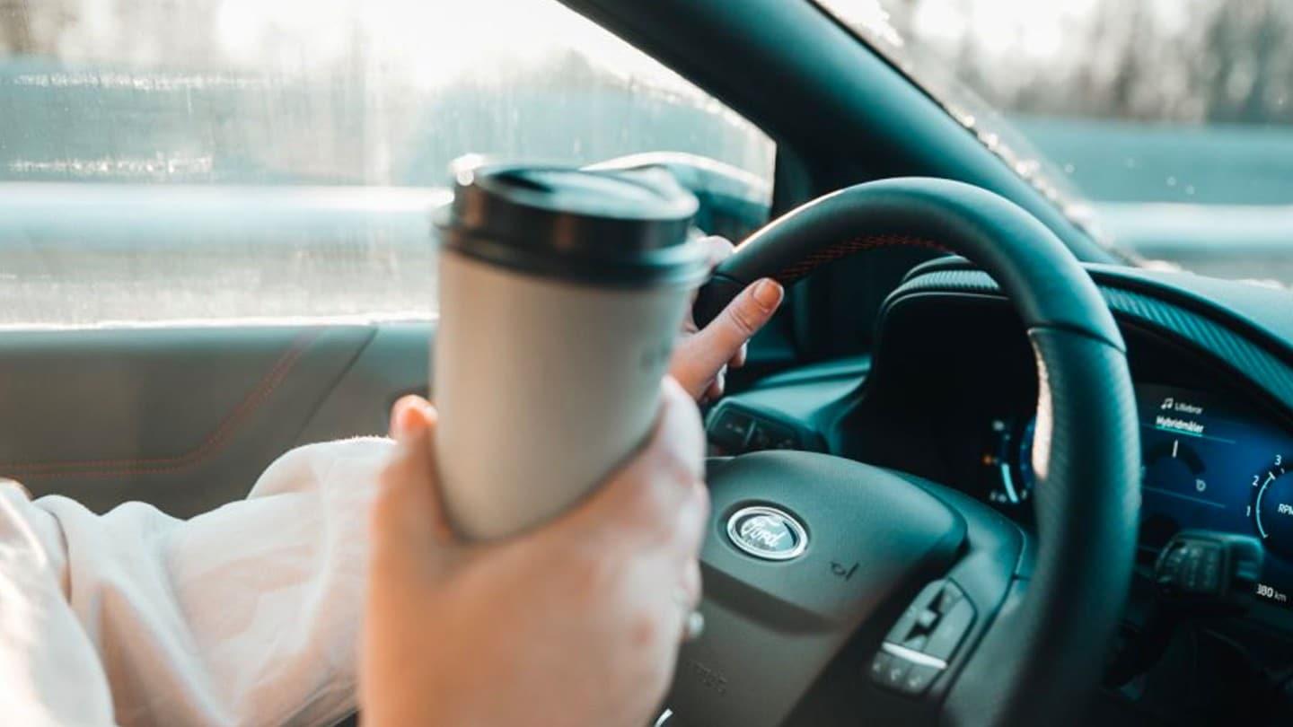 Man drinking coffee inside Ford car