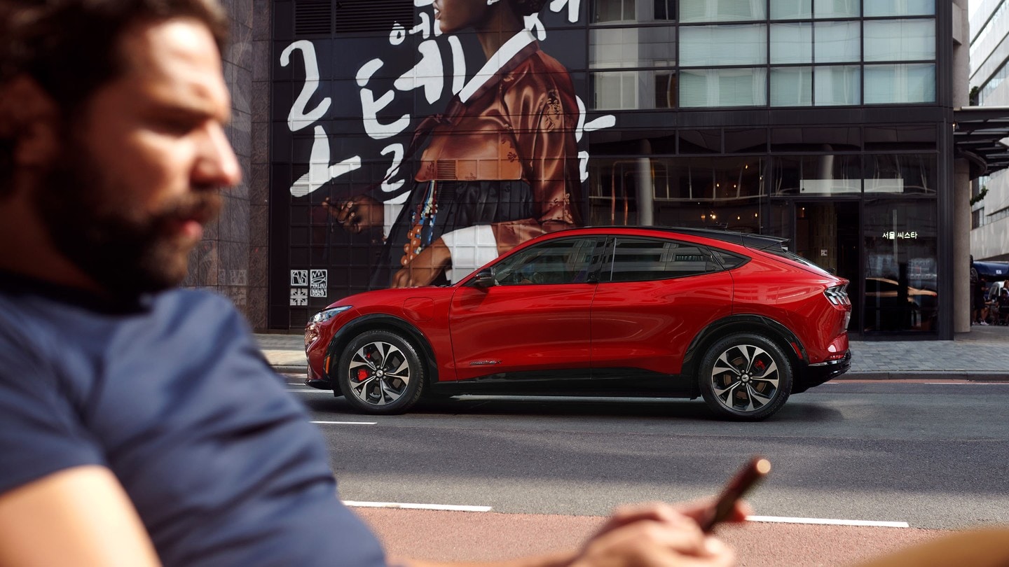 En mand kigger på sin telefon med en parkeret red Ford-elbil