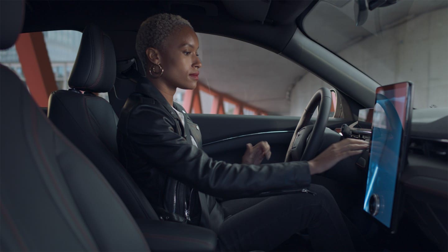 Kvinde sidder i en Ford Mustang Mach-E og bruger Next Generations touch-skærm