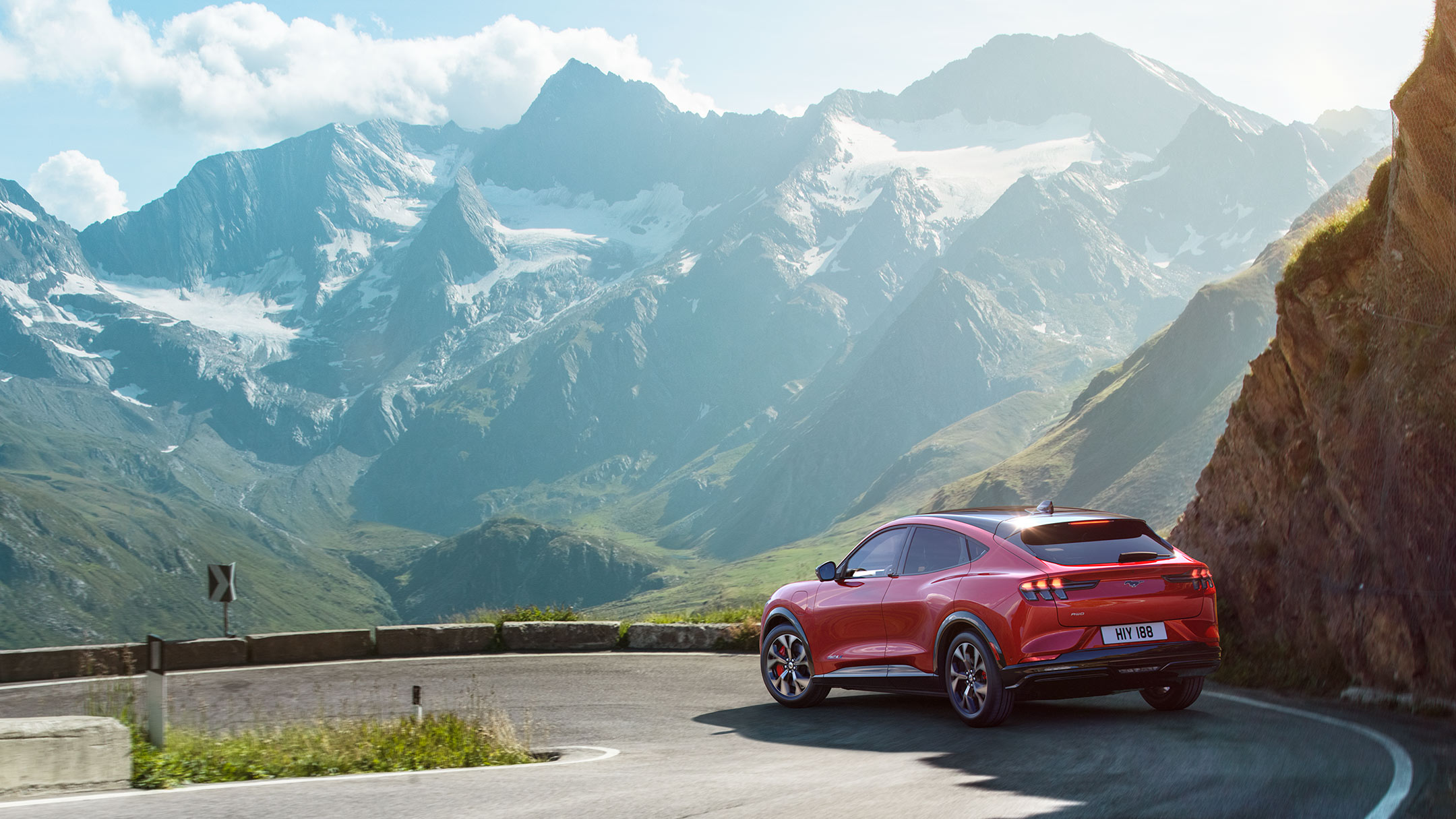 En rød, helt ny Ford Mustang Mach-E, der kører på vejen i bjergene