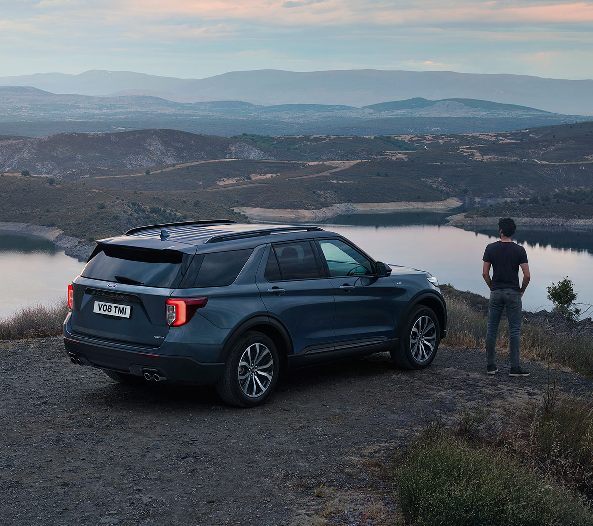 Ford Explorer parkeret ved en sø  i et kuperet område med en person stående ved siden af ​​med udsigt over landskabet